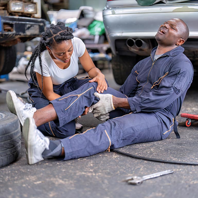 Un mecánico recibe ayuda tras un accidente en un taller.